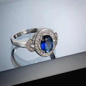 Detail of silver ring with oval blue gemstone and micro-paved cubic zirconia stones