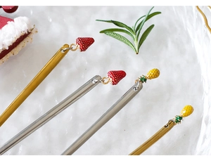 Detail of four creative metal fruit picks featuring strawberry and pineapple charms
