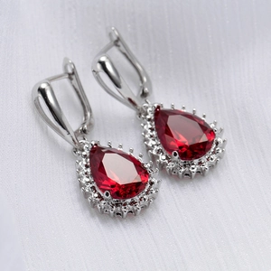 Macro shot of teardrop earrings with red pear-cut stones and claw-set white crystals