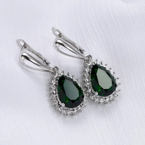 Detailed macro view of pear-cut emerald green zircon earrings with white diamond halo