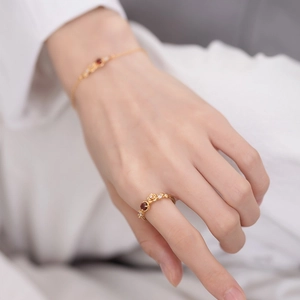 Detail of floral gold ring with red garnet gemstone and crystals on model's hand