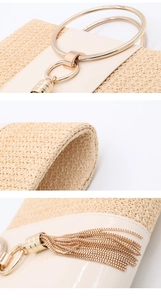 Detail of woven straw handbag with gold round handles and metallic tassel accents