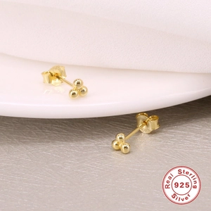 Macro shot of 925 sterling silver triple ball stud earrings with polished gold finish