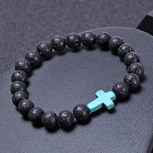 Lava rock stone bead bracelet with a blue turquoise cross charm on a black pedestal