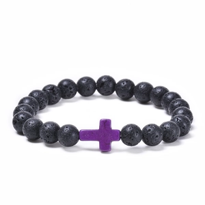 Detailed macro view of black lava rock beads and a purple synthetic turquoise cross charm