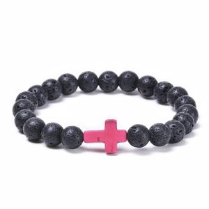 Detailed view of black lava rock beads and a pink cross pendant on the elastic bracelet