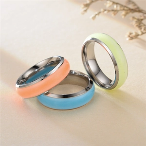 Close-up of three colorful glow-in-the-dark stainless steel rings in orange and blue
