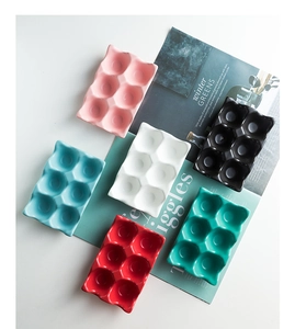 Detail of colorful 6-slot ceramic egg trays in pink, blue, black, and white finishes