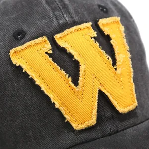 Macro view of yellow W embroidery on black denim baseball cap with frayed edges