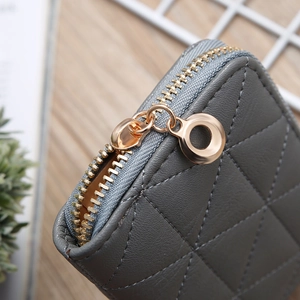 Close-up of grey quilted mini wallet featuring a premium golden metal zipper and stitching