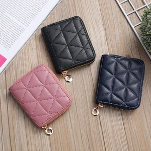 Three quilted mini wallets in black, pink, and navy blue with gold ring zippers