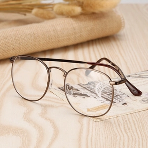 Vintage round metal eyeglass frames with dark brown finish on a rustic wooden background