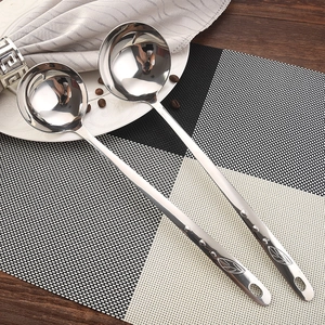 Polished stainless steel soup spoons with leaf pattern handles on a dining table