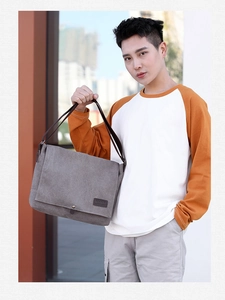 Outdoor shot of a man wearing a grey canvas messenger bag with a brown leather logo