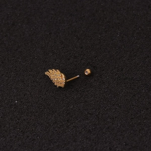 Golden wing-shaped ear piercing stud with sparkling cubic zirconia on dark sponge