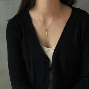 Close-up of a vintage golden key pendant necklace worn on a model in minimalist style
