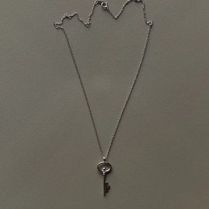 Macro shot of minimalist vintage silver key pendant necklace with a polished metallic finish