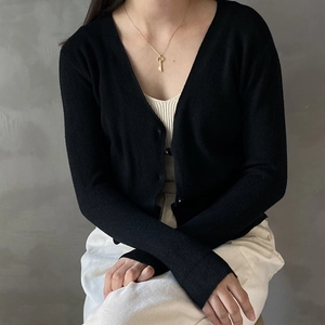 Detailed view of 925 silver vintage key necklace worn over a black knitted cardigan