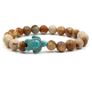 Detail of beaded bracelet featuring brown marble beads and a blue turquoise sea turtle charm