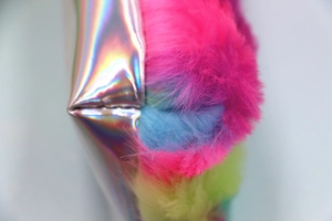 Dettaglio ravvicinato di pelliccia sintetica arcobaleno e materiale argento olografico