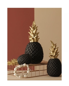 Set of three black and gold pineapple ornaments in a modern luxury home decor scene