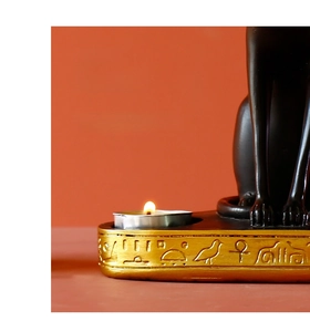 Macro detail of Egyptian cat goddess tea light holder with golden hieroglyphs and soft candlelight