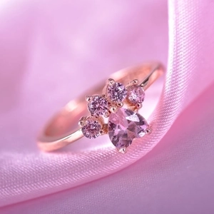 Adjustable rose gold cat paw ring with pink heart cubic zirconia on silk background