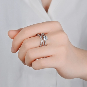 Sparkling silver criss-cross ring with central cubic zirconia on a female model finger