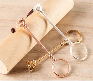 Detailed trio of rose-shaped cigarette holders in gold, silver, and rose gold metal
