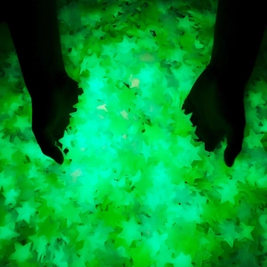 Hands holding glowing 3cm fluorescent star stickers for bedroom wall decoration