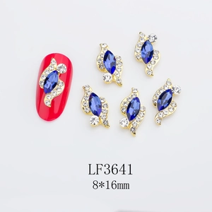 Detailed view of 8x16mm blue navette nail charm with gold base on red manicure