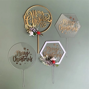 Detail view of four Merry Christmas acrylic cake toppers with red berries and pine cones