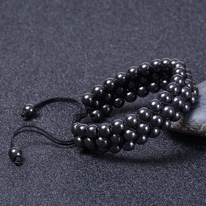 Detailed view of 6mm magnetic hematite beads on a three-layer adjustable woven bracelet