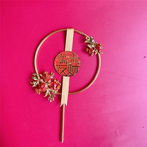 Detail of a golden metal ring cake topper with red berries and a golden Xi symbol
