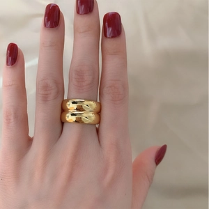 Macro shot of layered wide chunky 18K gold plated titanium rings on model's hand