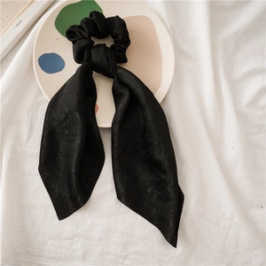 Close-up of black satin scrunchie with long ribbons on a decorative ceramic plate