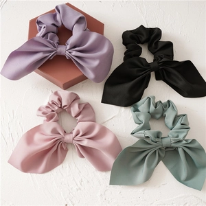 Close-up of pastel chiffon bow scrunchies with long streamers on textured background