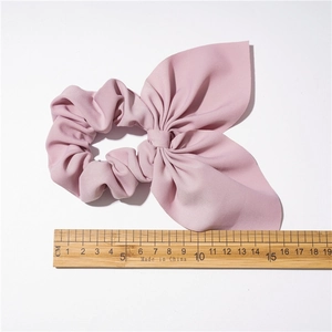 Pink bow knot scrunchie in soft fabric measured at 15cm on a white background