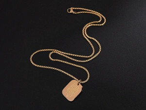 Detail of gold square pendant with Love Alone Could Waken Love engraving on black background