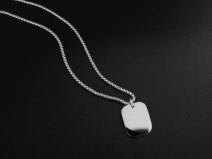 Macro detail of a silver rectangular square pendant with a metallic woven chain necklace
