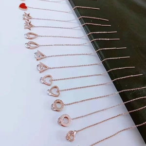 Macro shot of rose gold tassel earrings with heart and star charms on a black display