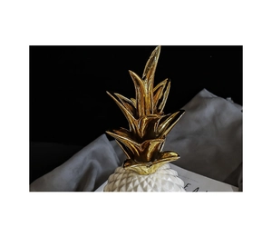 Detail of modern ceramic pineapple decor with golden metal leaves and geometric texture