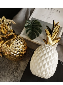 Close-up of golden and white ceramic pineapple ornaments with geometric diamond texture