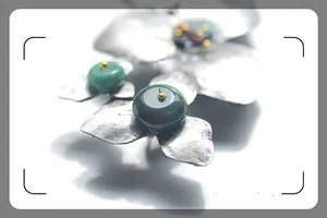 Macro detail of antique silver leaf brooch with green natural stones and golden beads
