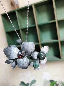 Macro detail of antique silver floral brooch with colorful natural stones and leaf design