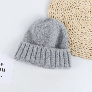 Macro shot of light gray knit beanie texture featuring thick wool vertical ribs and a rolled edge