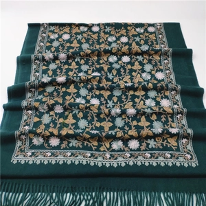 Close-up of dark green cashmere-like shawl with intricate floral embroidery and tassel fringe