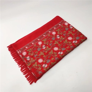 Detailed view of red cashmere shawl featuring intricate floral embroidery and tassel fringe