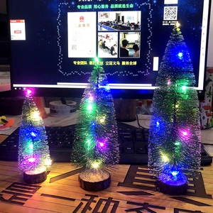 Close-up of three mini Christmas trees with colorful LED lights and wooden bases