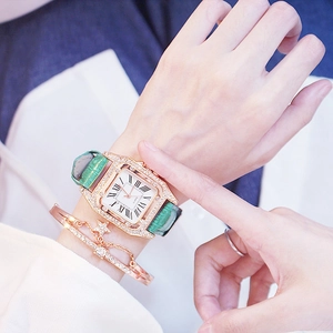 Macro detail of square quartz watch with green leather strap and star bracelet on wrist